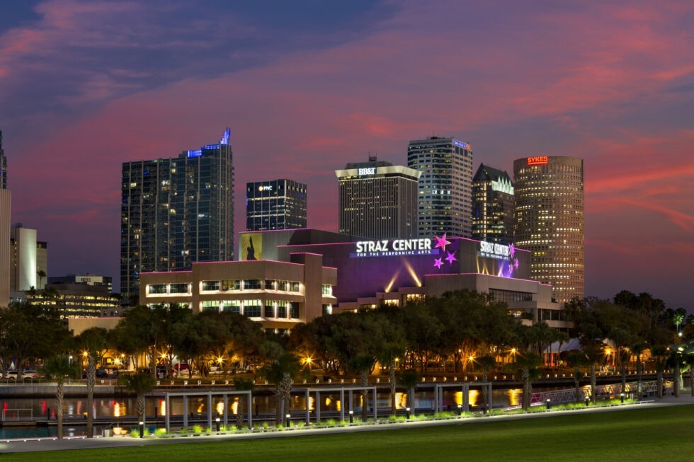 City skyline at dusk featuring the Straz Center for the Performing Arts, with a colorful sky and illuminated buildings in the background.